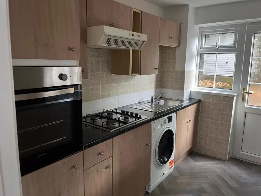 Clean fitted kitchen with oven, hob and washing machine in an empty rental