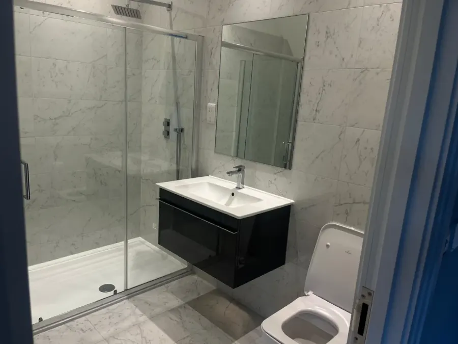 Clean walk-in shower with marble-effect tiles and a wall-hung basin